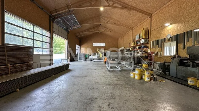 Große Halle mit Holzwänden, Betonboden und hohen Decken, ideal für Lagerung oder Werkstatt.