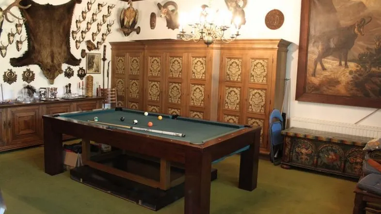 Geräumiges Wohnzimmer im traditionellen Stil mit Billardtisch und Jagdtrophäen an den Wänden.