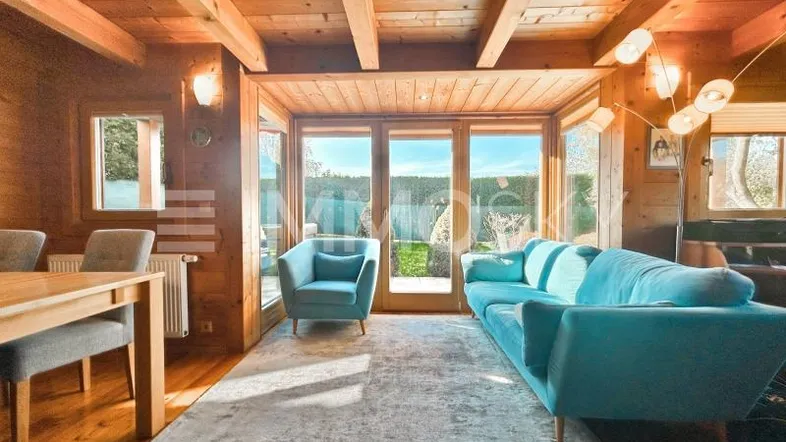 Helles Wohn- und Esszimmer mit Holzbalkendecke, gemütlicher Sitzecke und Zugang zum Garten.