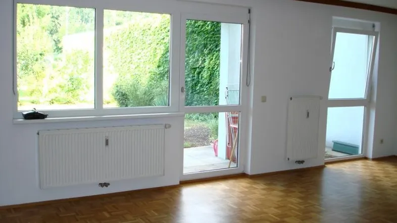 Helles Wohnzimmer mit Parkettboden, großen Fenstern und Zugang zur Terrasse.
