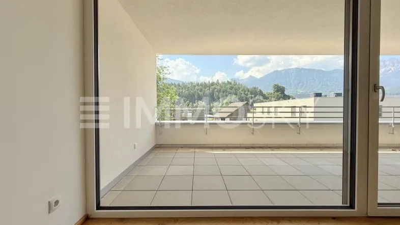 Heller Innenraum mit Holzboden und großem Zugang zu einer Terrasse mit Bergblick.