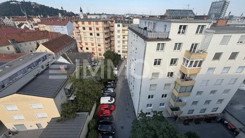 Panoramablick über die Stadt mit Wohngebäuden, einer Straße und parkenden Autos.