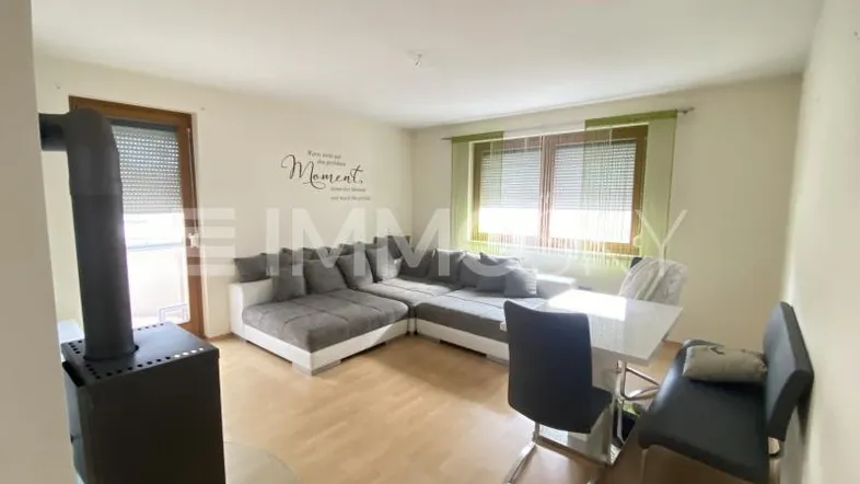 Heller Wohn- und Essbereich mit gemütlichem Ecksofa, Esstisch und einem Holzofen für zusätzliche Wärme.