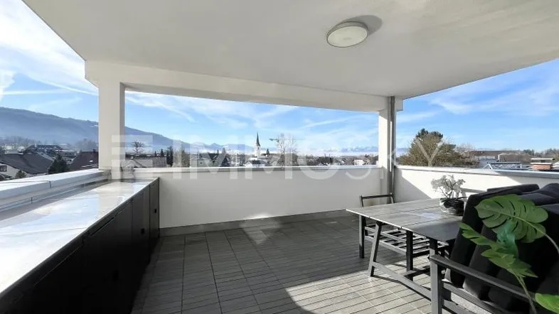 Geräumige überdachte Terrasse mit Sitzgelegenheiten und weitem Blick auf die umliegende Berglandschaft.