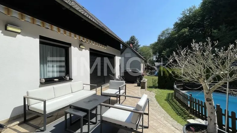 Geräumige Terrasse mit modernen Gartenmöbeln, angrenzendem Rasen und kleinem Poolbereich.