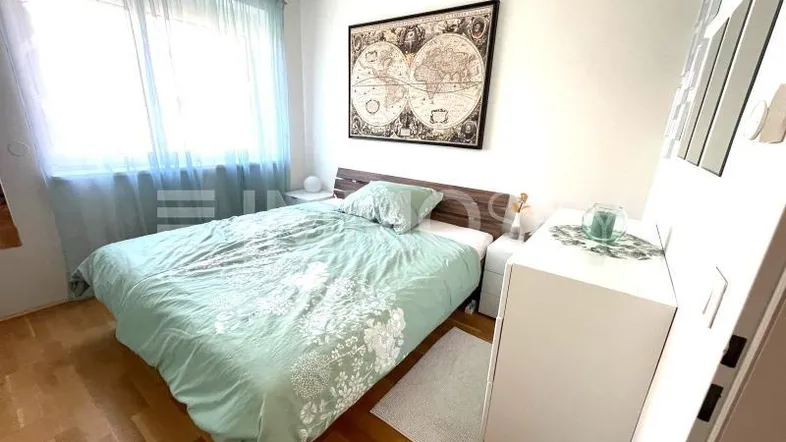 Helles Schlafzimmer mit Holzboden, großem Fenster und einem Weltkartenbild an der Wand.