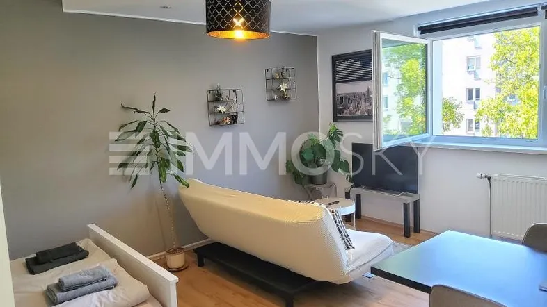 Helles Studio-Apartment mit Schlafbereich, Sofa, Esstisch und großem Fenster.