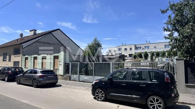 Älteres Gebäude mit Satteldach und verbarrikadierten Fenstern an einer Wohnstraße.