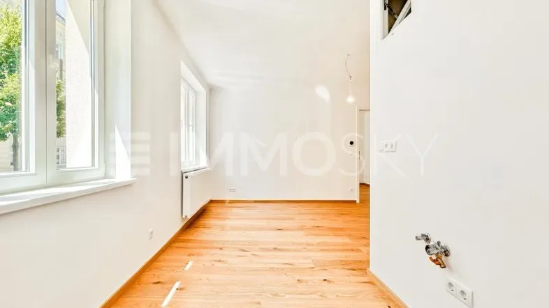 Helles Zimmer mit neuem Parkettboden und Fenstern, vorbereitet für eine Kücheninstallation.