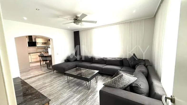 Geräumiges Wohnzimmer mit großem Ecksofa, modernem Couchtisch und offenem Zugang zur Küche.