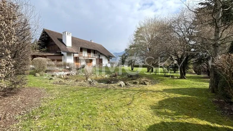 Großes Einfamilienhaus mit weitläufigem Garten und Blick auf die umliegende Landschaft.