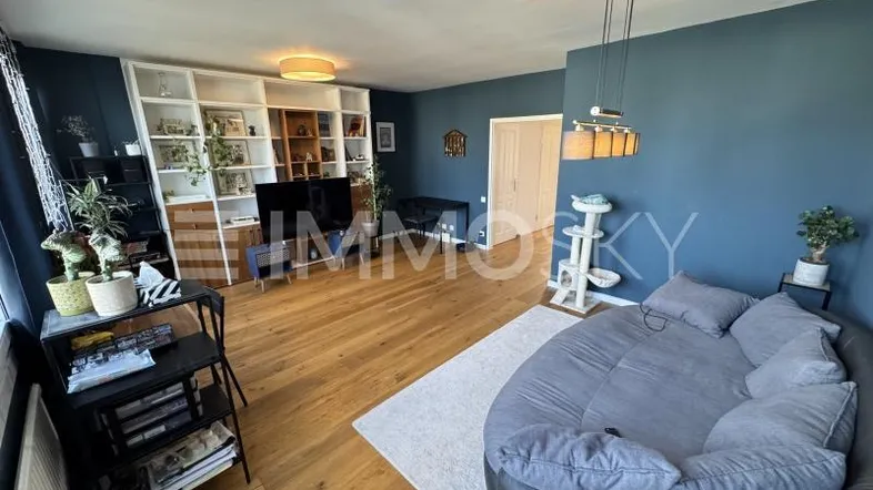 Helles Wohnzimmer mit Holzboden, blauen Wänden und einem großen runden Sofa.