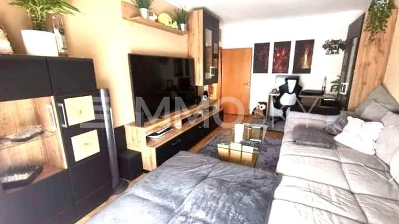 Gemütliches Wohnzimmer mit großem Sofa, Fernseher und integriertem Arbeitsbereich.