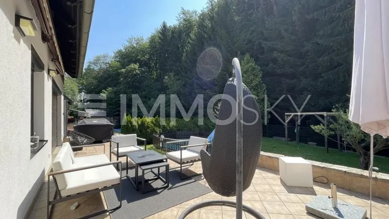 Geräumige Terrasse mit modernen Gartenmöbeln und Blick ins Grüne unter blauem Himmel.