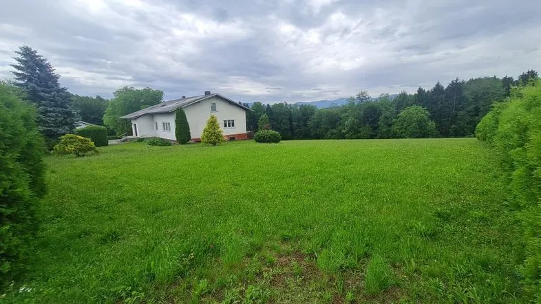 Einfamilienhaus mit großem Rasengrundstück und Blick auf die umliegende Natur und Berge.