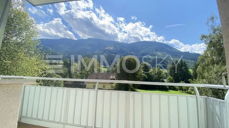 Balkon mit weitem Blick auf die umliegende Berglandschaft und grüne Natur.