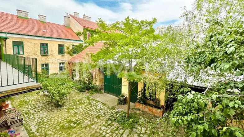 Grüner Innenhof mit Kopfsteinpflaster, Bäumen und umliegenden historischen Gebäuden, bietet eine ruhige Oase.
