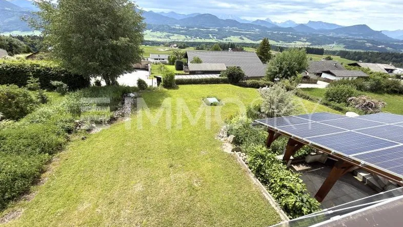 Weitläufiger Gartenbereich mit Rasenfläche, Bäumen und Blick auf die umliegende Berglandschaft.