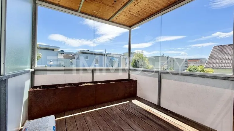 Verglaste Loggia mit Holzboden und Blick auf die Umgebung, ideal für entspannte Stunden im Freien.