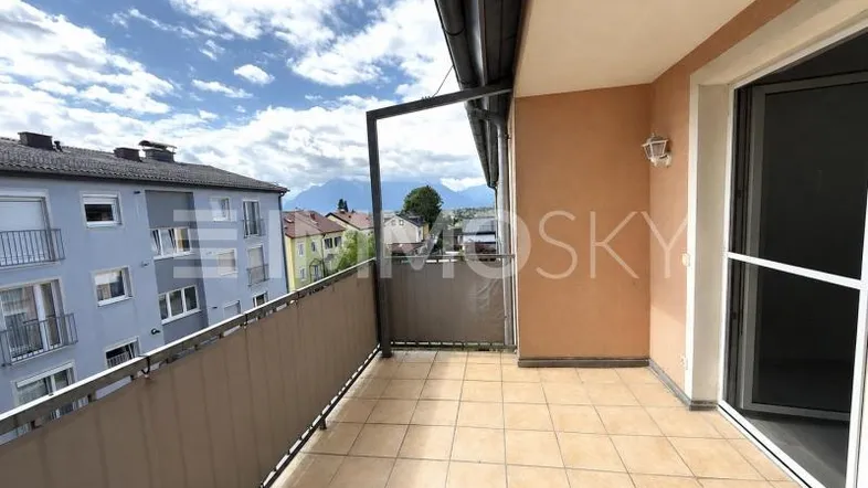 Geräumiger Balkon mit Fliesenboden und Blick auf die umliegende Wohngegend und Berge.
