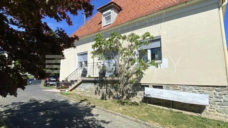 Ansicht der Hausfassade mit rotem Ziegeldach, beigen Wänden und einem kleinen Vorgarten.