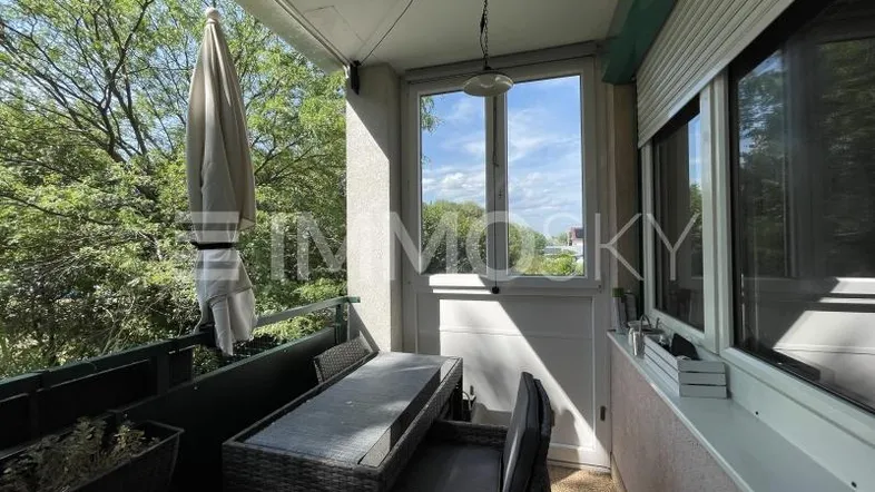 Helles Balkon mit Sitzgelegenheiten und Blick ins Grüne, ideal für entspannte Stunden im Freien.