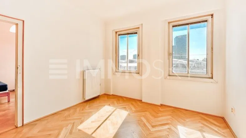 Helles Zimmer mit Fischgrätparkett und Blick auf die Stadt, ideal als Schlaf- oder Arbeitszimmer.