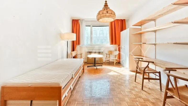 Helles Schlafzimmer mit Parkettboden, Einzelbett, Regalen und orangefarbenen Vorhängen.