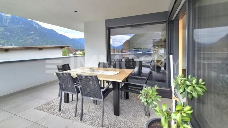 Geräumiger Balkon mit Esstisch, Stühlen und herrlichem Bergblick, ideal für Mahlzeiten im Freien.