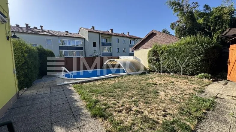 Hinterhof mit kleinem Pool, Rasenfläche und gepflastertem Bereich, umgeben von Hecken.