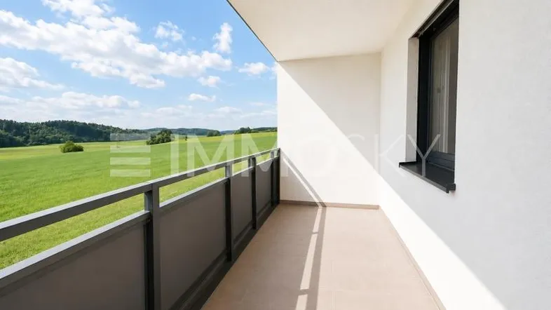 Heller Balkon mit Fliesenboden und weitem Blick über grüne Felder und Landschaft.