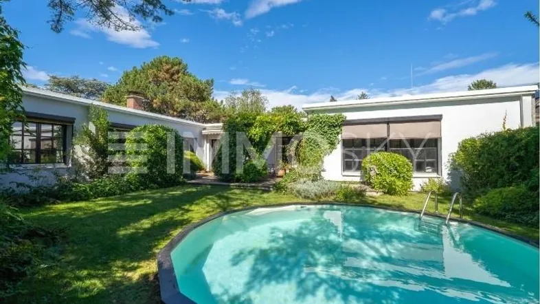 Großer Garten mit privatem Pool und Blick auf das moderne Haus unter blauem Himmel.