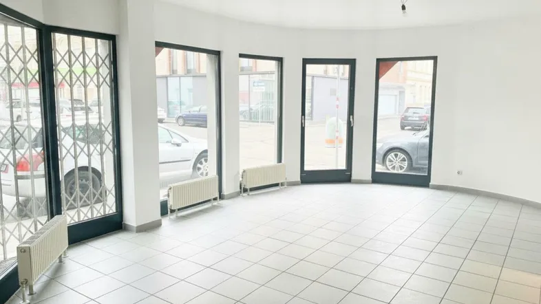 Heller Gewerberaum mit großen Schaufenstern und Fliesenboden, ideal für Ladenlokal oder Büro.