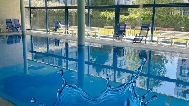 Großer Innenpoolbereich mit Wellness-Charakter und viel Tageslicht durch Panoramafenster.