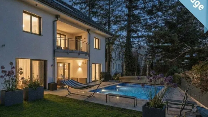 Großzügiger Gartenbereich mit Pool, Liegefläche und beleuchteter Fassade am Abend.