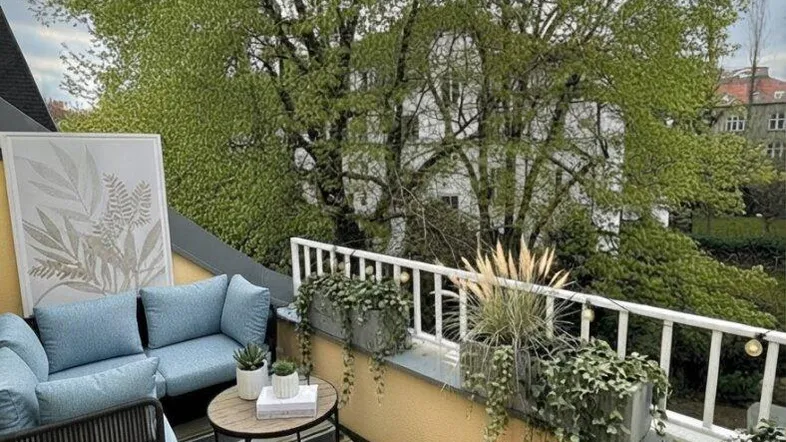 Gemütlicher Balkon mit modernen Sitzgelegenheiten, Pflanzen und einem schönen Blick ins Grüne.