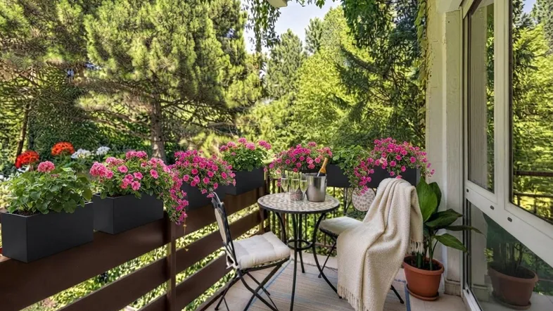 Ein gemütlicher Balkon mit üppigen Blumenkästen, Sitzgelegenheiten und einem schönen Blick ins Grüne.