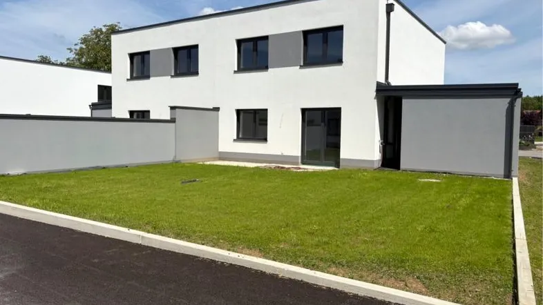 Modernes Doppelhaus mit weißer Fassade, dunklen Akzenten und gepflegtem Rasen im Vordergrund.