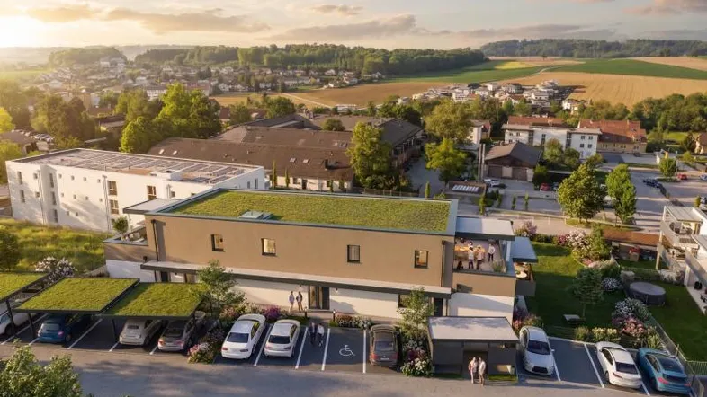 Luftaufnahme einer modernen Wohnanlage mit Gründach und Carports in ländlicher Umgebung.