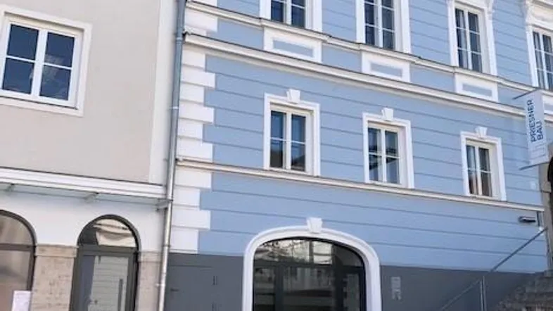 Historisches Gebäude mit blauer Fassade und weißen Verzierungen, direkt an der Straße gelegen.