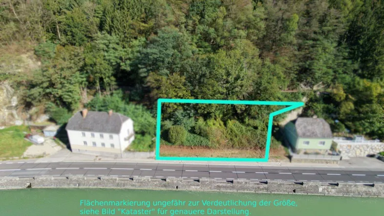 Luftaufnahme eines Grundstücks am Flussufer, umgeben von grüner Natur und Wald.