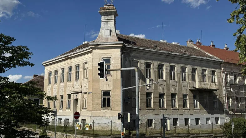 Historisches Gebäude mit markantem Turm und klassischer Architektur unter blauem Himmel.
