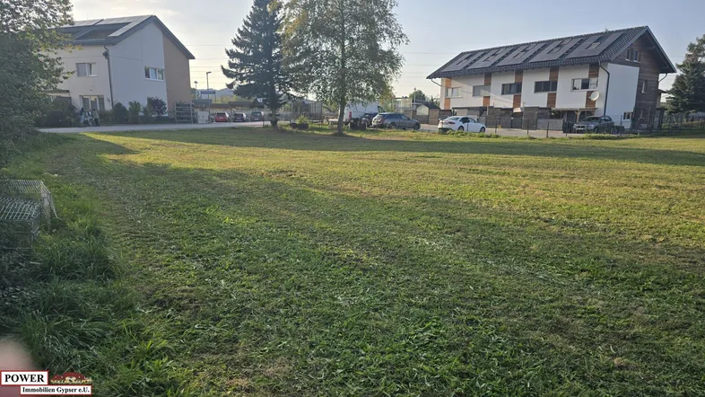 Weitläufige Grünfläche mit umliegenden Wohnhäusern und Bäumen unter einem klaren Himmel.