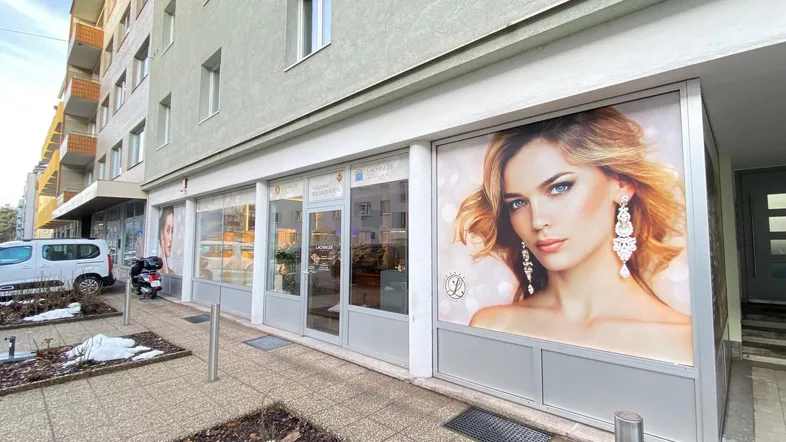 Außenansicht eines Geschäftsgebäudes mit großen Schaufenstern und Werbeflächen an der Fassade.