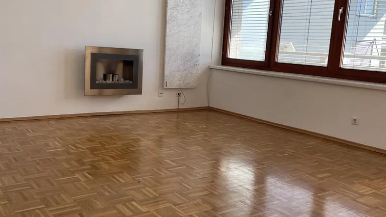 Helles Wohnzimmer mit Parkettboden, großen Fenstern und modernem Wandkamin.