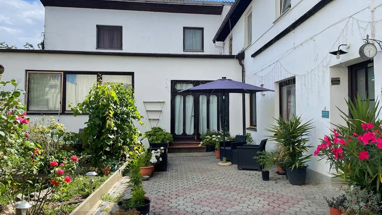 Gepflasterter Innenhof mit Gartenmöbeln, Sonnenschirm und blühenden Pflanzen.