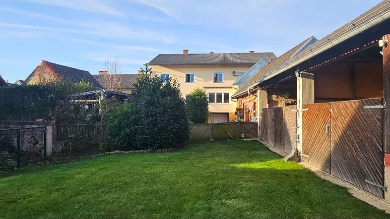 Großer, gepflegter Gartenbereich mit Rasenfläche und Nebengebäude, umgeben von weiteren Wohnhäusern.