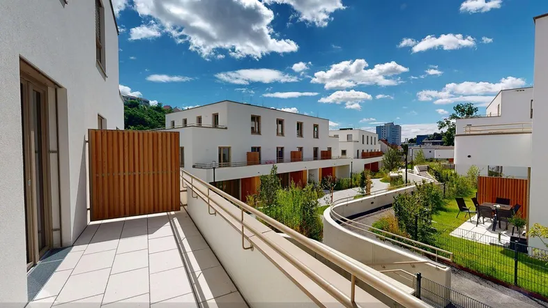 Moderne Wohnanlage mit großem Balkon und Blick auf die gepflegte Außenanlage.