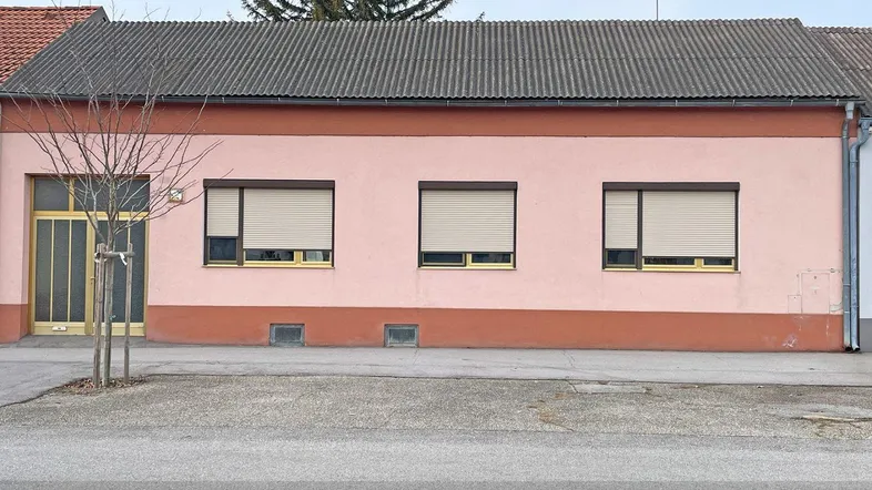 Die Fassade des Hauses präsentiert sich in einem warmen Rosaton mit Rollläden an den Fenstern.