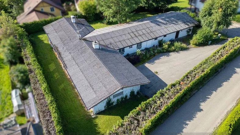 Luftaufnahme des L-förmigen Gebäudes mit gepflegter Hecke und grüner Umgebung.